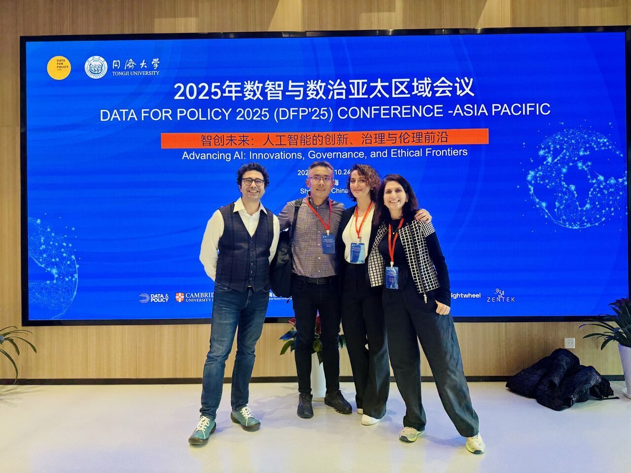 Tuba Bircan with three colleagues in front of the Data for Policy 2025 Asia-Pacific conference screen at Tongji University