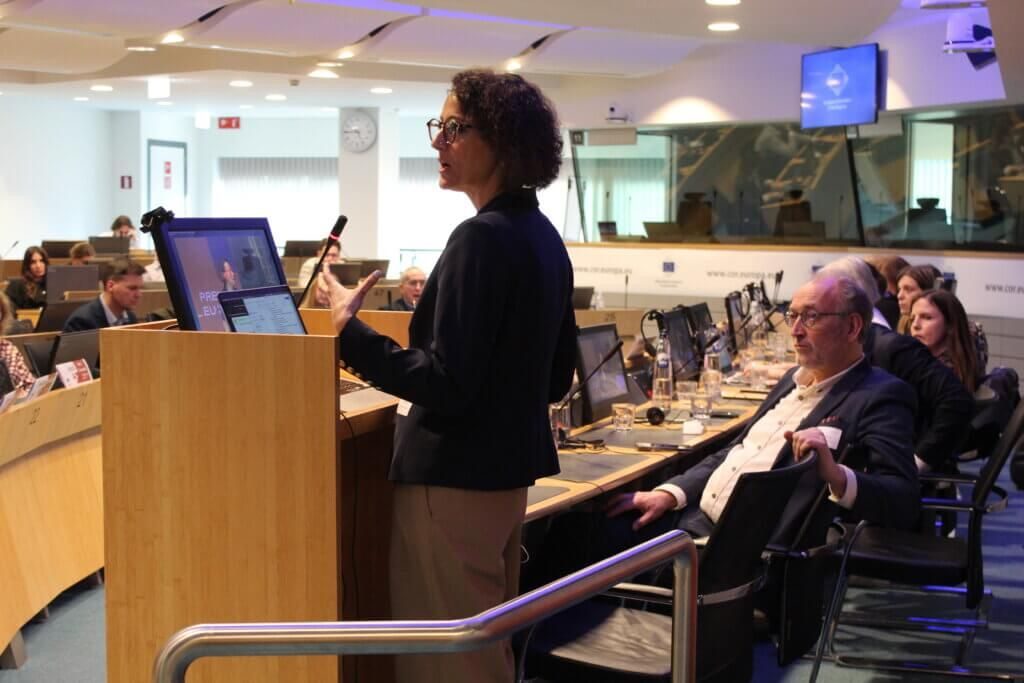 Tuba Bircan speaking at a podium in a European Union meeting room